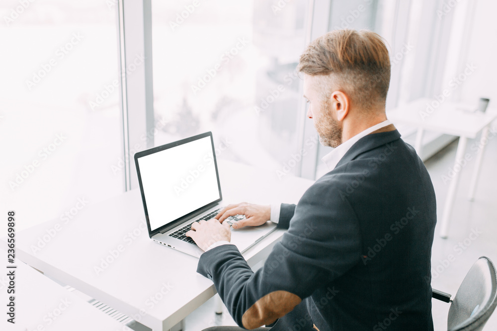 An employee at the laptop, the business aspects. Bright and stylish office interior and cut out the background.