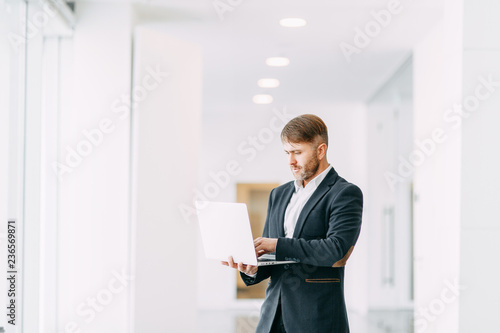 An employee at the laptop, the business aspects. Bright and stylish office interior and cut out the background.