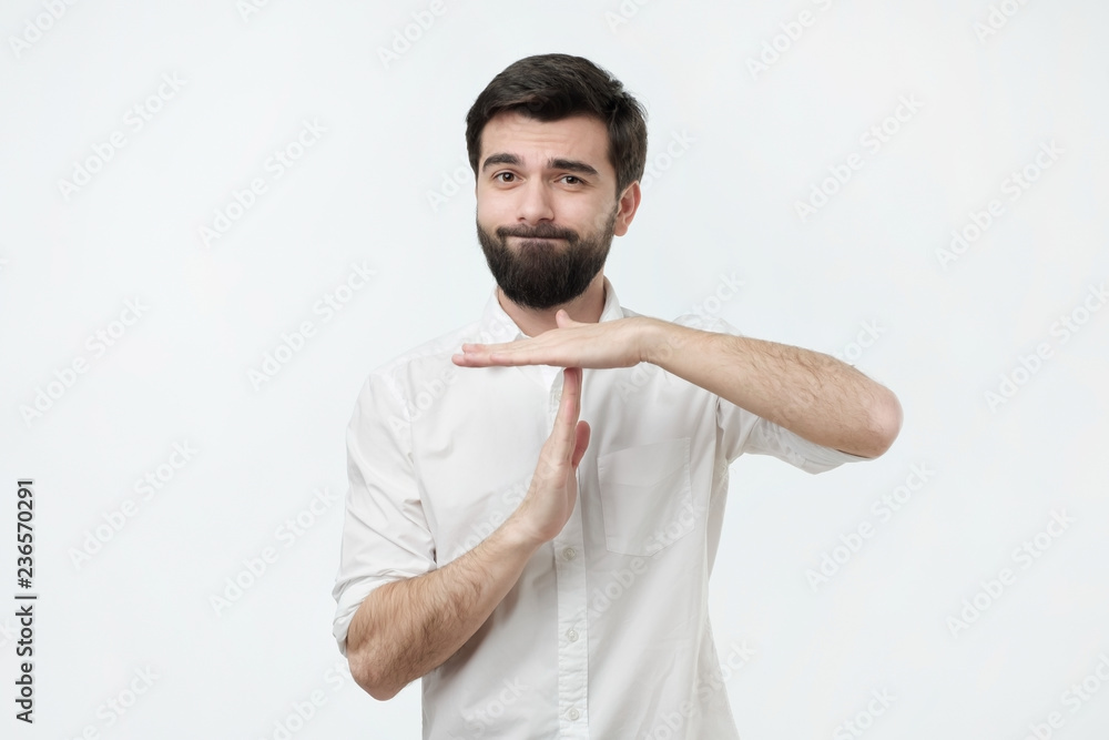 Spanish young man with black beard making time out gesture over grey background. I need a minute to rest. Spanish young man with black beard making time out gesture over grey background. I need a minute to rest.