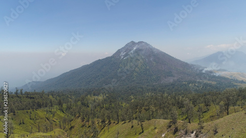 mountain landscape slopes mountains covered with green tropical forest. Java, Indonesia. aerial view mountain forest with large trees and green grass.