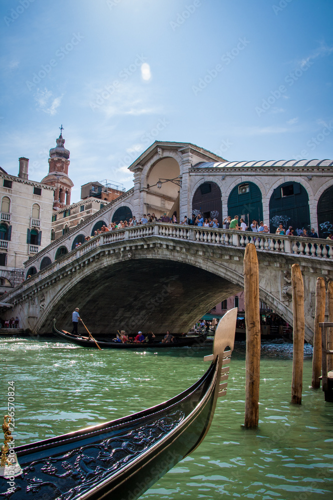 The Rialto bridge on Grand canal is a famous landmark of Venice ,Italy, with blue sky ,and gondola boat over water