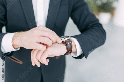 Business man looking at his watch, it's time to do. Bright office interior, for business meetings.