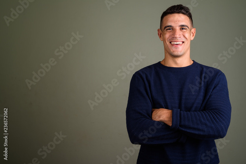Young handsome man wearing sweater against colored background