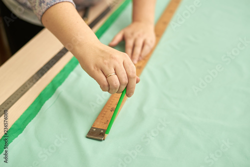 Woman cut out material green pencil for clothing.