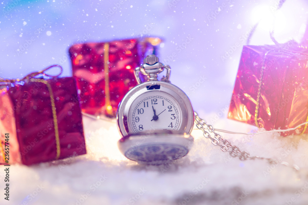 Pocket watch with a dial in the snow with gifts on the eve of holidays. Waiting for the magic of Christmas and new year