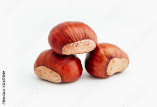 Three roasted chestnuts in a pile, isolated on white background.