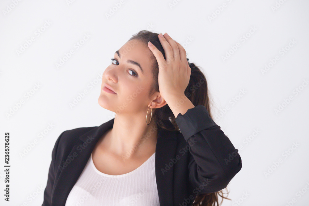 Beautiful smiling young businesswoman posing in black jacket. Portrait of brunette attractive manager touching hair and looking at camera. Isolated on white. Beauty concept Beautiful smiling young businesswoman posing in black jacket. Portrait of brunette attractive manager touching hair and looking at camera. Isolated on white. Beauty concept