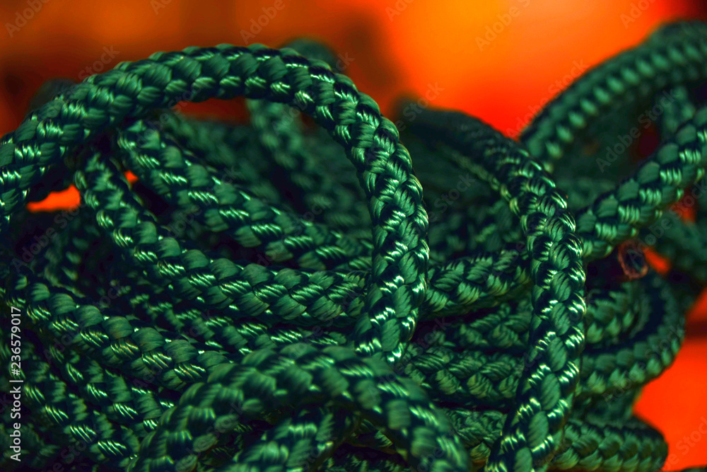 Obraz premium green rope rolled strings in front of orange background, new green rope macro shot for the shipping or health or sports industry