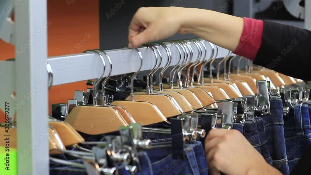 women's hands choose jeans on the hanger in the store women's hands choose jeans on the hanger in the store