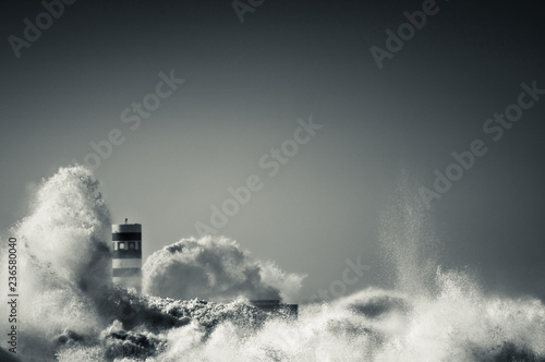 lighthouse with a big wave of water from the ocean with blu sky © Michele