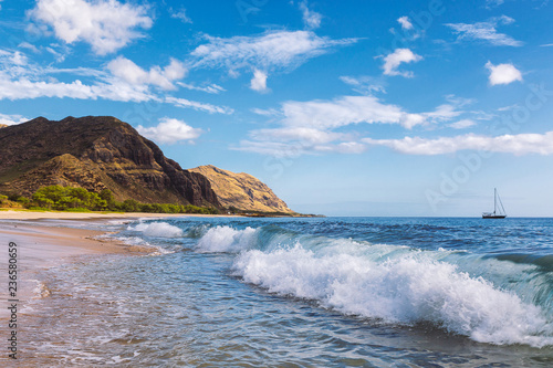 Makua beach view of the wave with beatiful mountains and a sailboat in the background  Oahu island  Hawaii