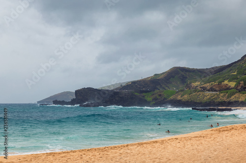 Oahu beach with people swimming in big waves