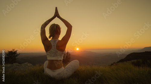 Fototapeta Naklejka Na Ścianę i Meble -  CLOSE UP: Active woman doing yoga in the mountains on a sunny summer evening.