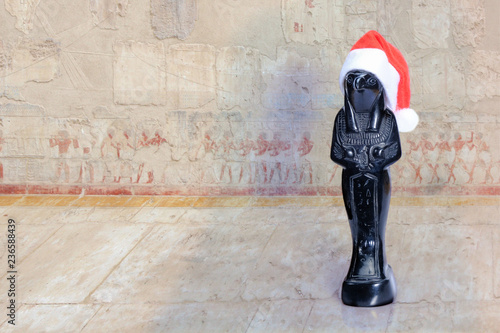 Statuette of the egyptian god Horus in a red Santa Claus hat