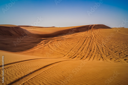 Tire tracks through the desert sand dunes. Feeling lost and alone in this world.