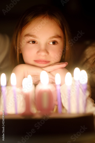 Photography Cute ten years old girl making a wish before blowing candles on her birthday cake