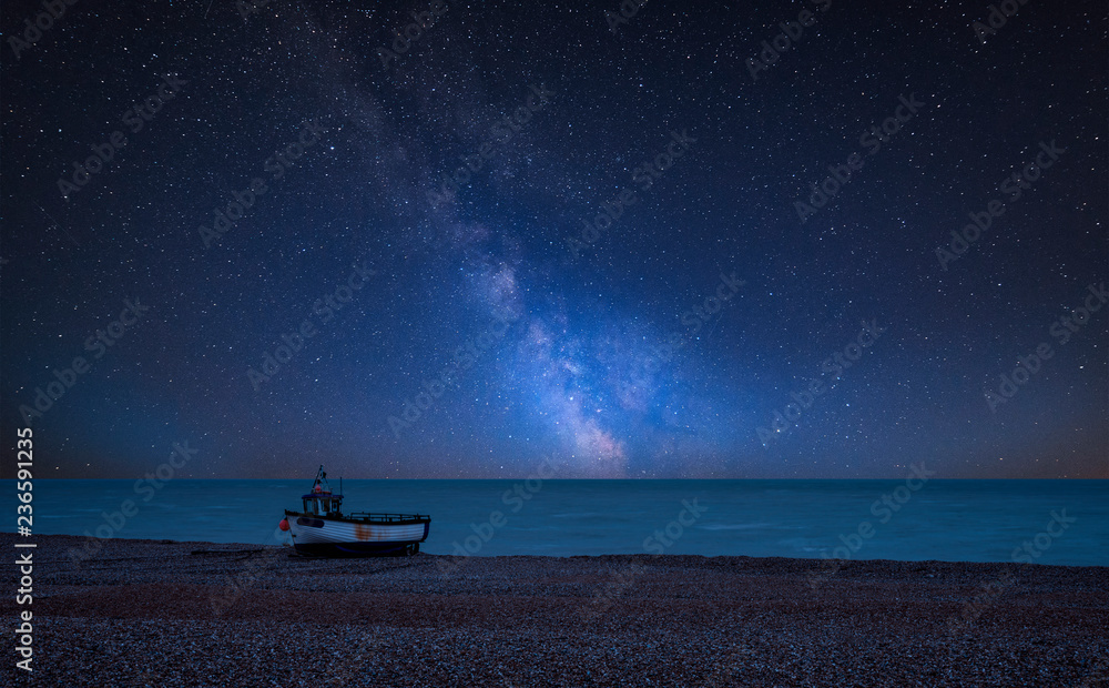 Vibrant Milky Way composite image over landscape of Abandoned derelict fishing boats on shingle beach