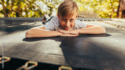 Small boy lying on trampoline outdoors