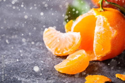 Fresh delicious mandarin, tangerine, clementine with green leaf on gray background. Ripe citrus fruits.Creative minimalistic food concept.Drawn Snowfall. Copy space for Text.