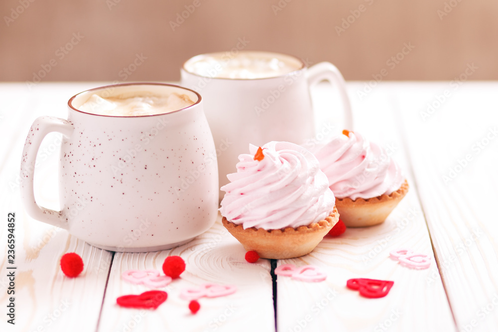 Two cups of coffee and cupcakes with pink cream for Valentine's Day or Birthday, wedding day. White wooden background. Selective focus Two cups of coffee and cupcakes with pink cream for Valentine's Day or Birthday, wedding day. White wooden background. Selective focus
