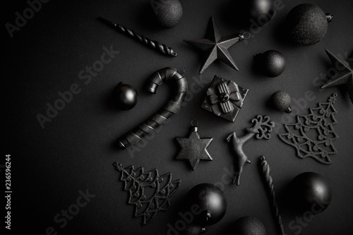 Christmas minimalistic and simple composition in mat black color. Christmas gifts, decorations on black background. Flat lay, top view with copy space