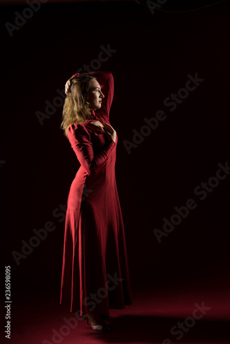 Lady in red gown standing and posing in studio. Portrait of beautiful elegant woman in evening dress