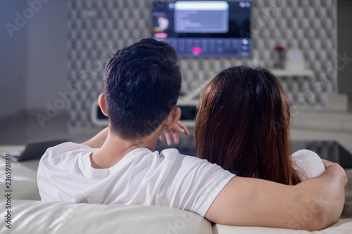 Young couple watching television at home
