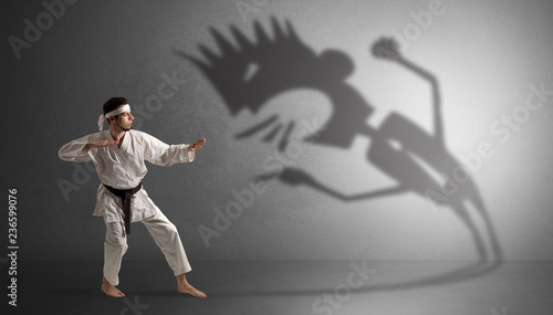 Young karate man fighting with a big black scary shadow 