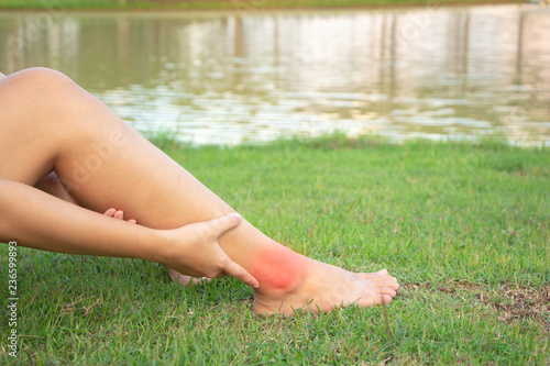 Woman massaging her painful foot, red highlighted on pain area, health care concept.