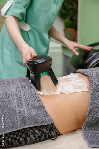 Woman getting cryolipolysis fat treatment in professional cosmetic cabinet photo