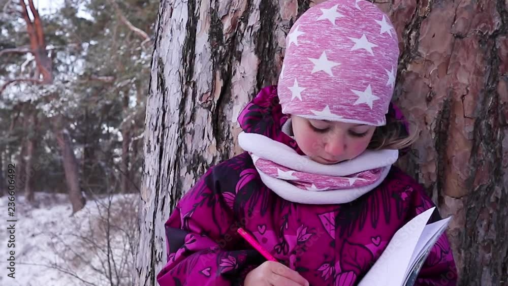 little girl draws a winter landscape in the forest little girl draws a winter landscape in the forest