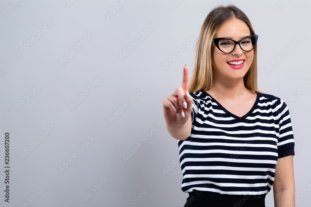 Young woman pointing at something on a gray background Young woman pointing at something on a gray background