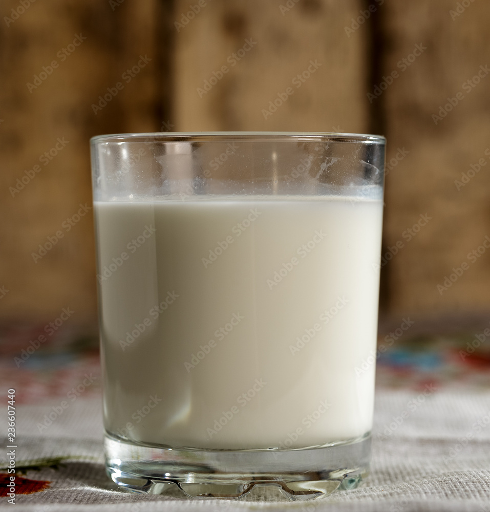 A glass of milk stands on a burlap on the background of old boards. A glass of milk stands on a burlap on the background of old boards.