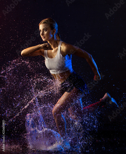 Young girl running in the dark in water splash