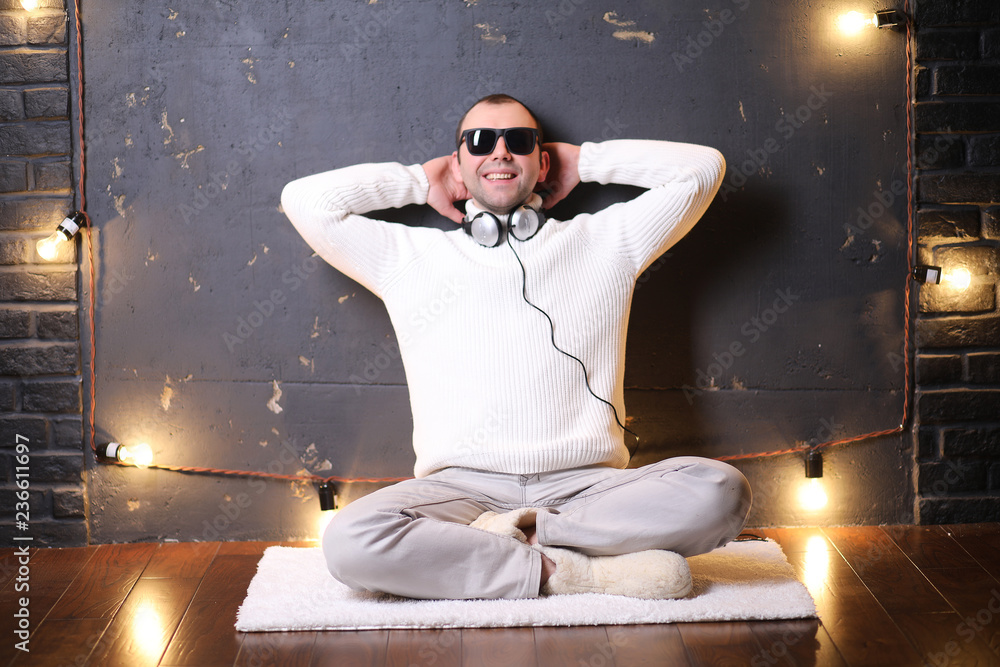 A man in a white sweater listens to music