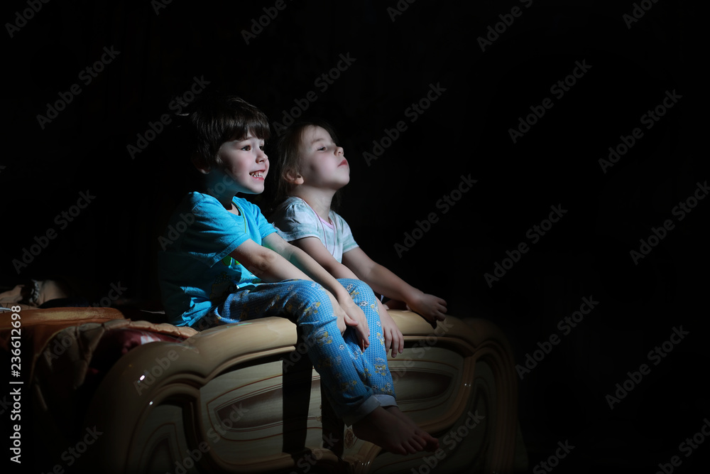 Small children in a dark room watching TV Small children in a dark room watching TV
