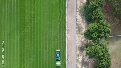 Large Lawn mower cutting green grass in a Soccer field - Top down aerial footage