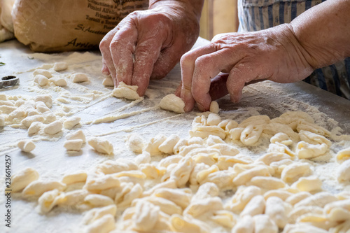 Hands of Italian woman making traditional fresh pasta on a marble table