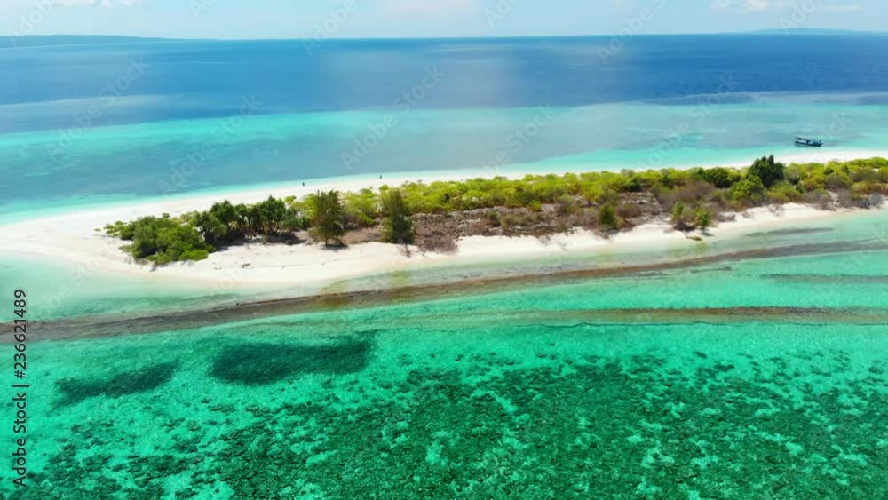 Aerial: Flying over idyllic atoll, scenic travel destination Maldives Polinesia. Blue lagoon and turquoise coral reef. Shot in Wakatobi National Park, Indonesia
