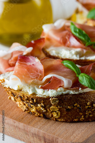 Italian tomato, prosciutto, jamon, ham and cheese bruschetta. Tapas, antipasti with chopped vegetables, herbs and oil on grilled ciabatta and baguette bread.