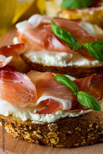 Italian tomato, prosciutto, jamon, ham and cheese bruschetta. Tapas, antipasti with chopped vegetables, herbs and oil on grilled ciabatta and baguette bread.