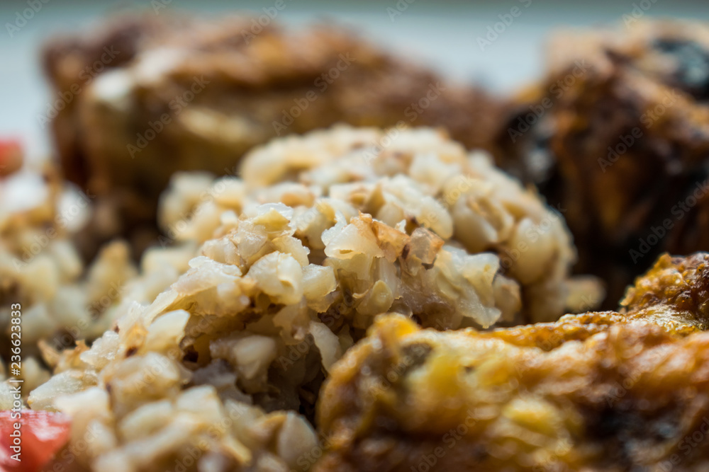 Fried, crispy chicken with boiled buckwheat porridge and slices of red tomato. Russian cuisine. Simple homemade food. Fried, crispy chicken with boiled buckwheat porridge and slices of red tomato. Russian cuisine. Simple homemade food.