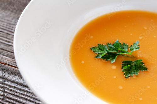 Vegetarian dish. Pumpkin soup with carrots, onions, garlic, olive oil, salt, coconut milk in a white plate.