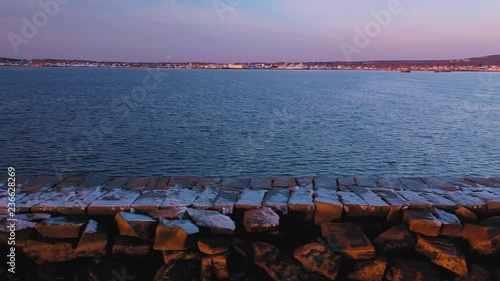 Close aerial slide along a snow dusted rocky breakwater in Rockland Maine photo