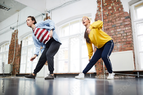 Small group of active girls doing street dance exercises while training in studio