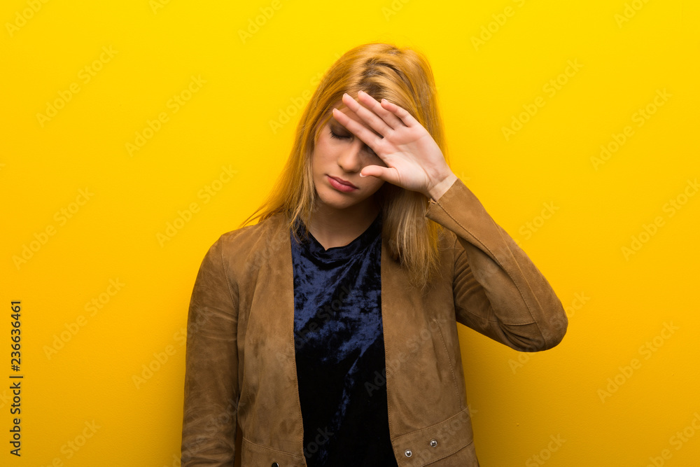 Blonde girl on vibrant yellow background with tired and sick expression