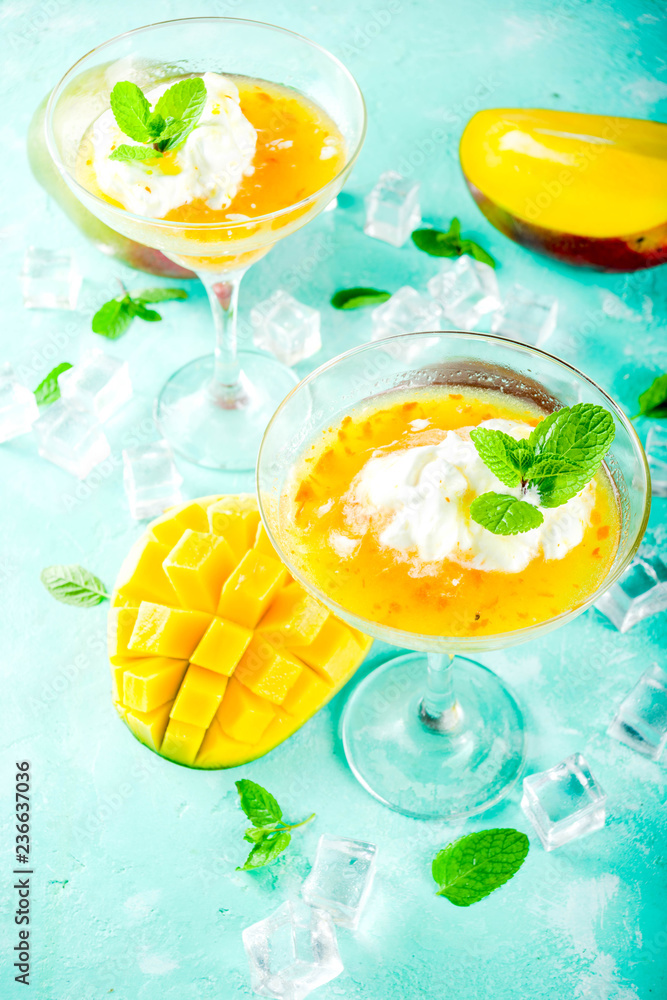 Tropical mango floating margarita cocktails with coconut ice cream, light blue background copy space