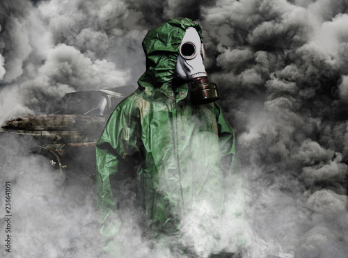 Man in gas mask and cloak for chemical protection in smoke of vehicles
