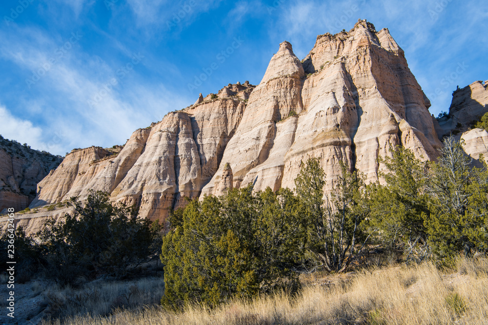 Steep, eroded rock formation with multiple sharp peaks under a blue sky with wispy clouds at Kasha-Katuwe Tent Rocks National Monument, New Mexico