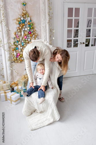 Happy family Portrait In Home - father, pregnant mother and their little son. Happy new year. decorated Christmas tree. Christmas morning in bright living room.